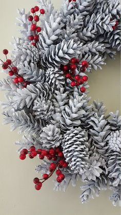 a wreath made out of pine cones and red berries