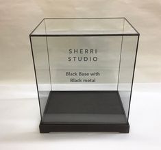 a glass display case with black metal on the bottom and sherril studio logo