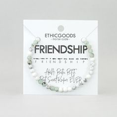 the bracelet is made with white and green beads, which are attached to a card