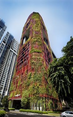 a tall building covered in green plants next to other buildings