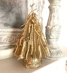 a gold christmas tree sitting on top of a white mantle