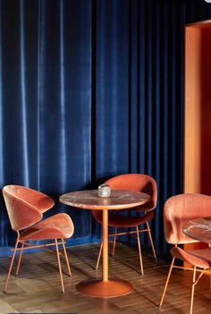 three chairs and a table in front of a blue curtain