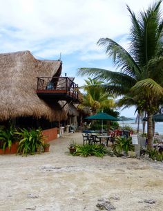 a thatched roof house on the beach with tables and chairs