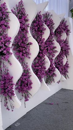 purple flowers are growing on the side of a white wall