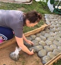 a woman kneeling down next to a pile of sandbags and bags filled with rocks