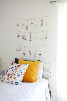 a white bed topped with lots of pillows next to a wall mounted necklaces on it