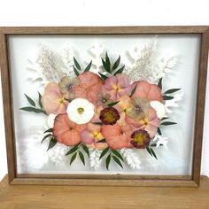 a wooden frame with flowers in it on a table next to a white and brown wall