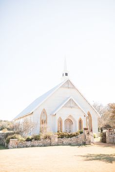 a white church with a steeple and flowers in the foreground