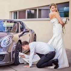 a man kneeling down next to a woman in front of a car