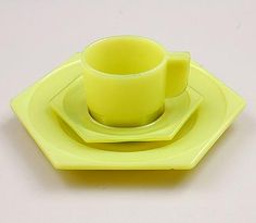 a yellow cup and saucer sitting on top of a green plate with a white background