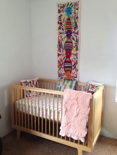 a baby crib in a room with a wall hanging on the wall behind it