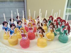 there are many little princess figurines on the cake plate with toothpicks in them