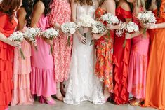 a group of women standing next to each other wearing dresses and holding bouquets in their hands