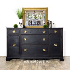 a black dresser with gold handles and knobs in front of a dining room mirror