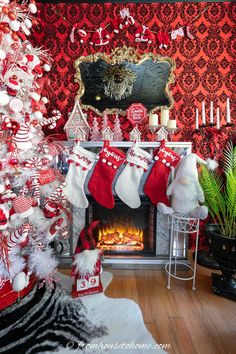 a decorated christmas tree in front of a fire place with stockings hanging from the mantle