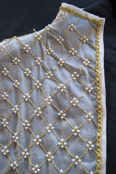 a piece of cloth with gold thread and pearls on it