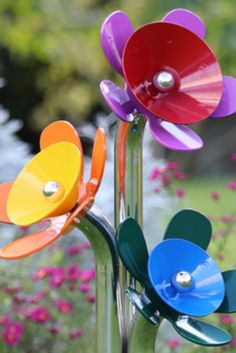 three colorful flowers are in a glass vase with metal stems and pearls on the petals