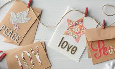 some paper tags are hanging from string on a white wooden table with snowflakes