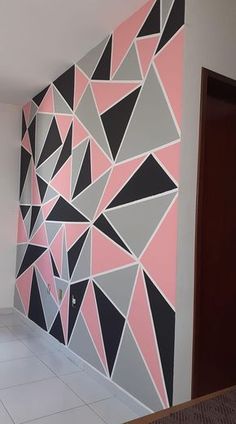 a room with a large wall painted in pink and grey triangles on the wall, next to a doorway