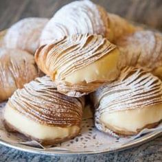 several pastries on a plate with powdered sugar and icing are sitting on the table