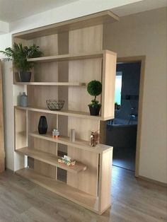 a living room with a book shelf and potted plants