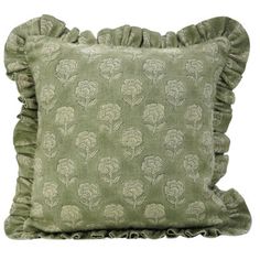 a green pillow with ruffled edges and flowers on the front, sitting against a white background