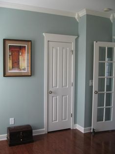 an image of a room with blue walls and white trim on the door, along with a brown trunk