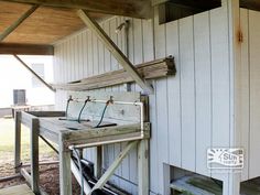 a wooden bench sitting on top of a porch next to a white building with wood slats