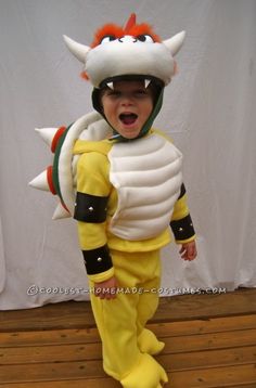 a little boy dressed in a costume that looks like a dragon with horns and tail