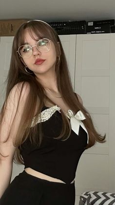 a woman with long hair wearing glasses and a black top is posing for the camera