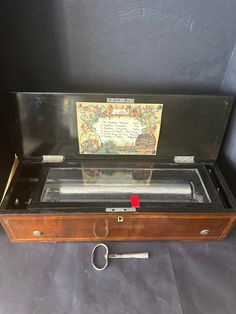 an old wooden box with a key in it and a card on the top shelf