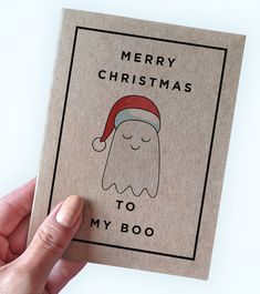 a hand holding a christmas card with a ghost wearing a santa's hat and text merry christmas to my boo