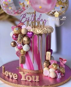 a pink and gold birthday cake with balloons