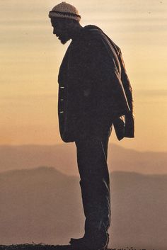 a man standing on top of a hill with his back to the camera looking down