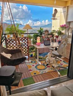 a balcony with chairs, tables and a laptop on the table in front of an open window