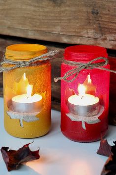 three jars with candles in them sitting on a table next to some leaves and string