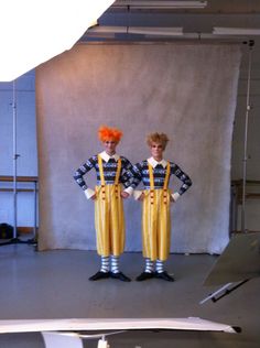 two men in yellow overalls and orange hair standing next to each other on a stage