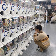 a woman squatting down in front of a rack of wii video game controllers at a store