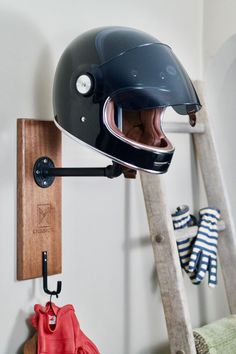 a motorcycle helmet mounted to the side of a wooden shelf next to a coat rack