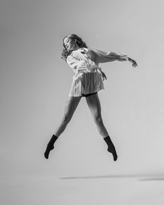 a woman is jumping in the air with her legs spread out and one leg up