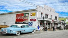 an old car is parked in front of a store on the side of the road