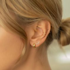 a close up of a woman's ear with gold and diamond earrings on it