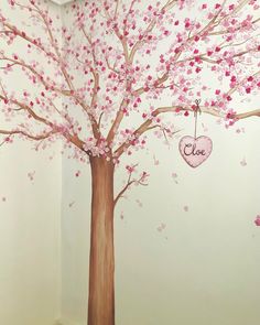 a tree painted with pink flowers and a heart hanging from it's trunk in a corner