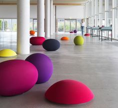 colorful balls are lined up in the middle of a large room with columns and windows