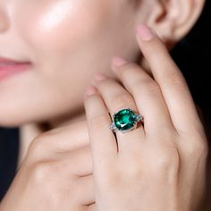 a close up of a person wearing a ring with a green gemstone on it