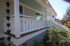 the front porch of a house with white railings and lanterns on it's balconies