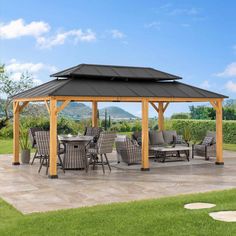 a gazebo sitting on top of a patio next to a lush green field and blue sky