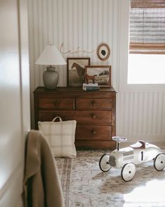 a wooden toy car sitting on top of a rug in a bedroom next to a dresser