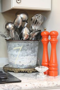 an old bucket filled with kitchen utensils on top of a counter