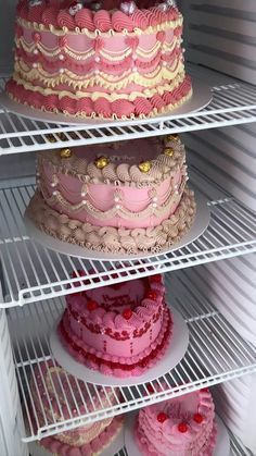 three tiered cakes are on the shelves in a refrigerator, and one has pink frosting